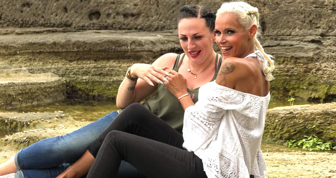 Zwei Frauen teilen sich einen glücklichen Typen im Freien